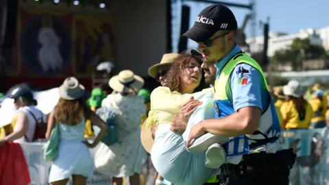 Getty Images A woman is carried by a police officer after collapsing in high temperatures in Lisbon in 2023