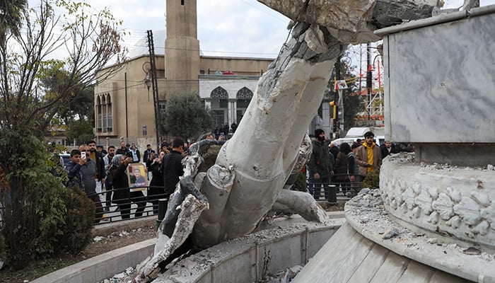 People stand near a damaged statue of former Syrian president Hafez al-Assad after Syrian rebels announced that they have ousted President Bashar al-Assad, in Qamishli, Syria December 8, 2024. — Reuters