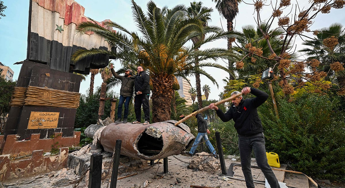 People stand atop a toppled statue of Syrias late president Hafez al-Assad in Damascus on December 8, 2024, after end of President Bashar al-Assads rule following rebel offensive. — AFP