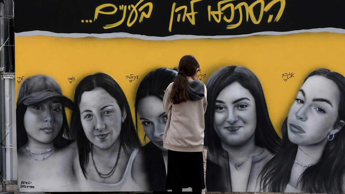 A girl pauses at a mural of female Israeli soldiers