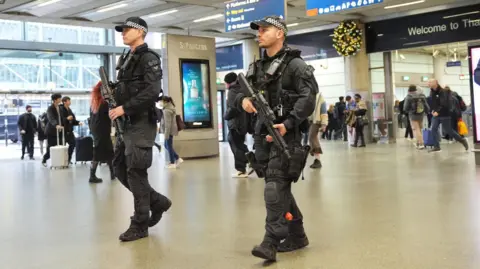 PA Media Two armed policemen walking through St Pancras International station, London