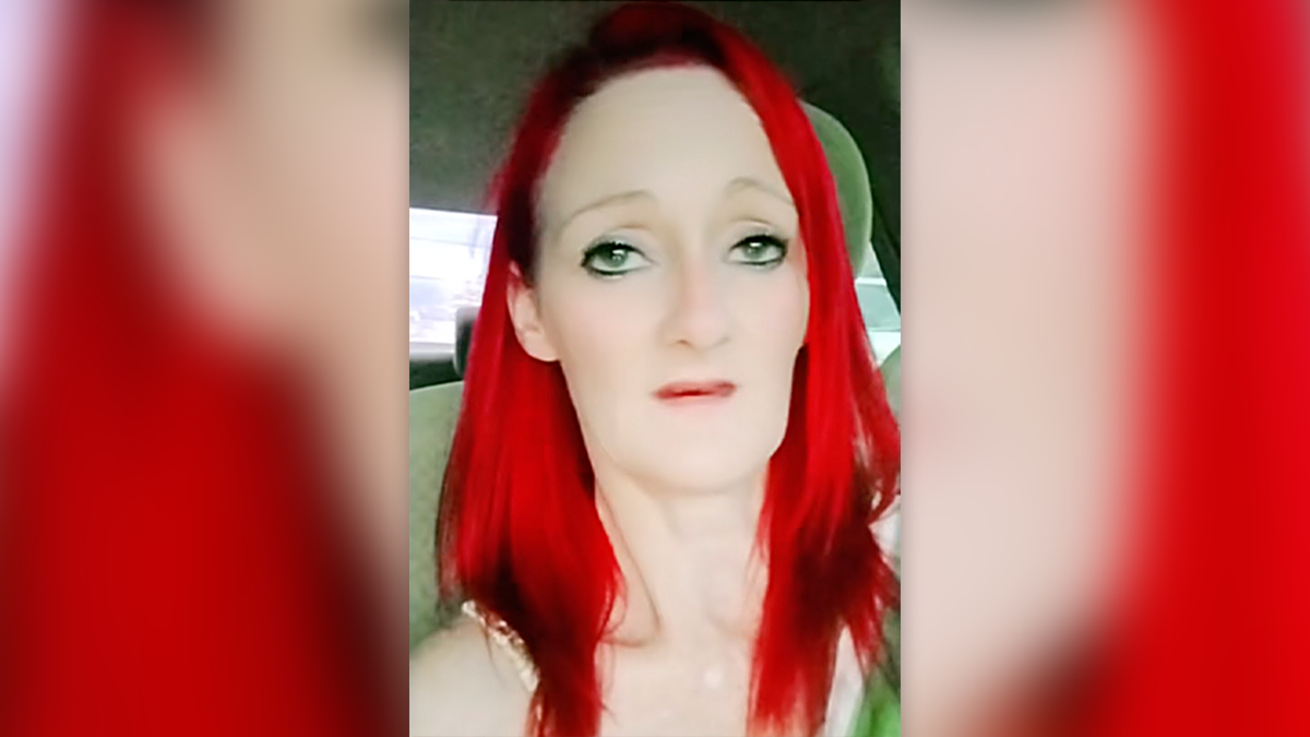 Heather Wright in a still image taken from video, sitting in her car, talking into a phone camera, with red hair and a green shirt